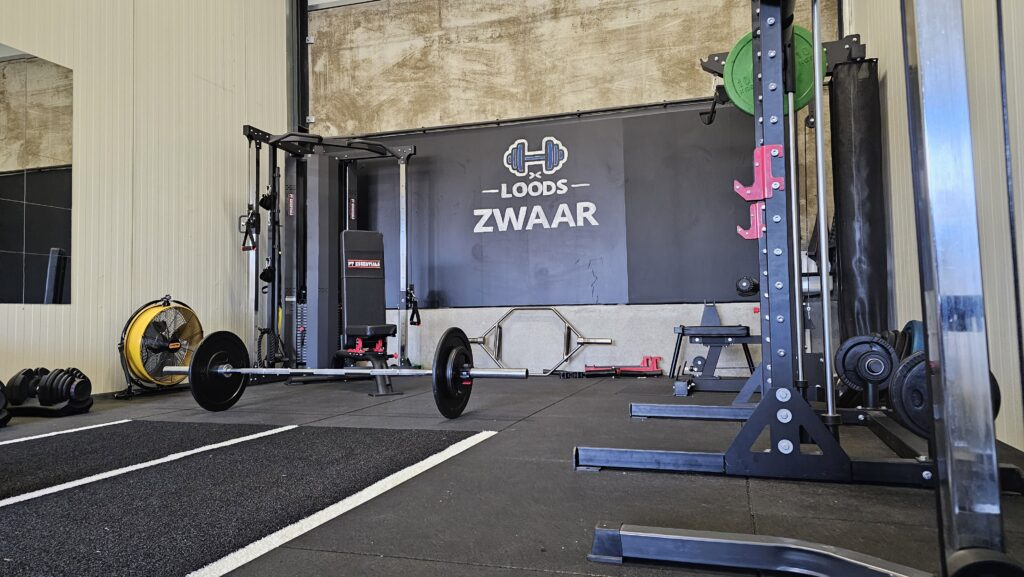 De trainingsruimte van Loods-Zwaar met rack, halters en kabelstation